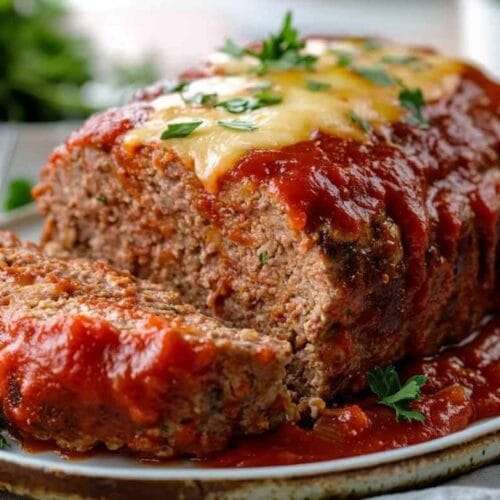 Pain de viande avec sauce tomate, fromage fondant sur le dessus et garniture de persil frais.